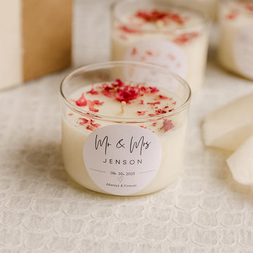 A personalized glass soy wax candle with Mr & Mrs on the label with a customized wedding date. There are red embedded rose petals on top of the candle.