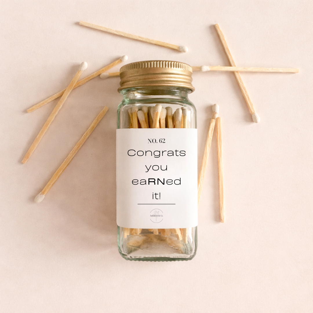 Jar of matches and pink candle with engraved name in a box on a pink and yellow background