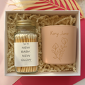 Gift set with a jar of matches and a pink candle labeled 'Kory June' in a box.