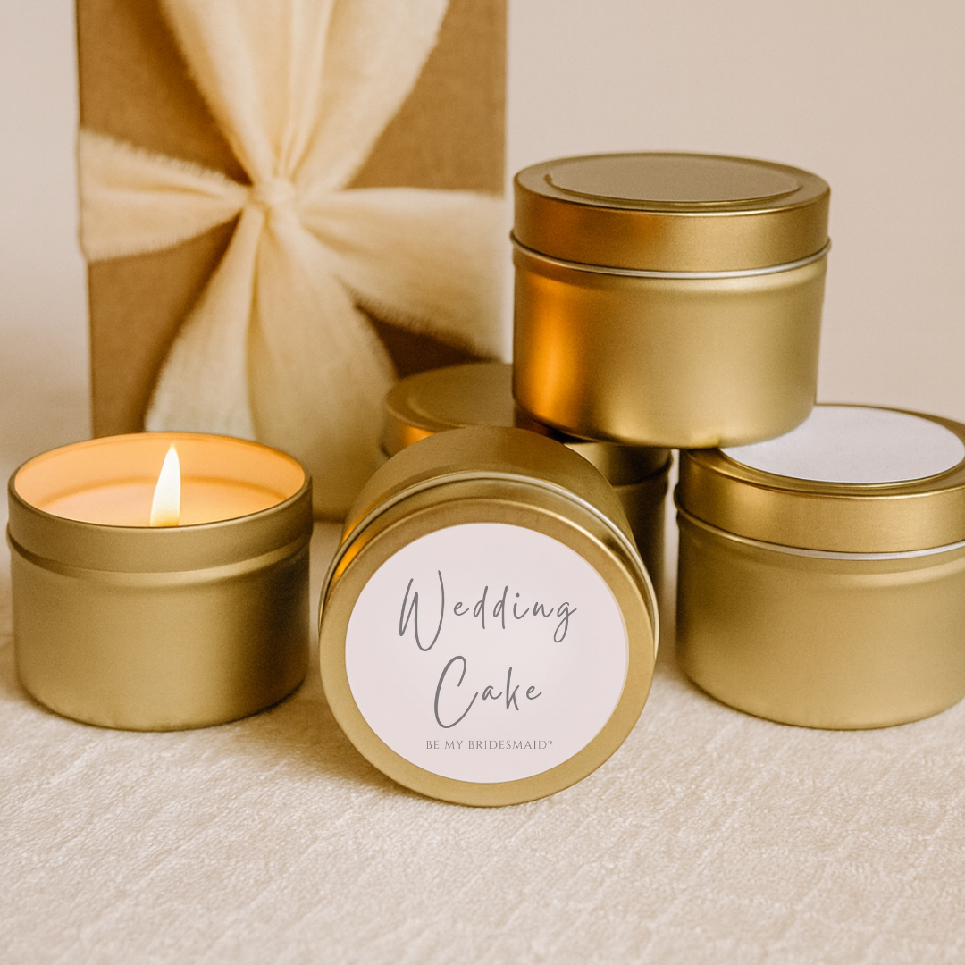 Gold candle tins with 'Wedding Cake' label and one lit candle on a beige background