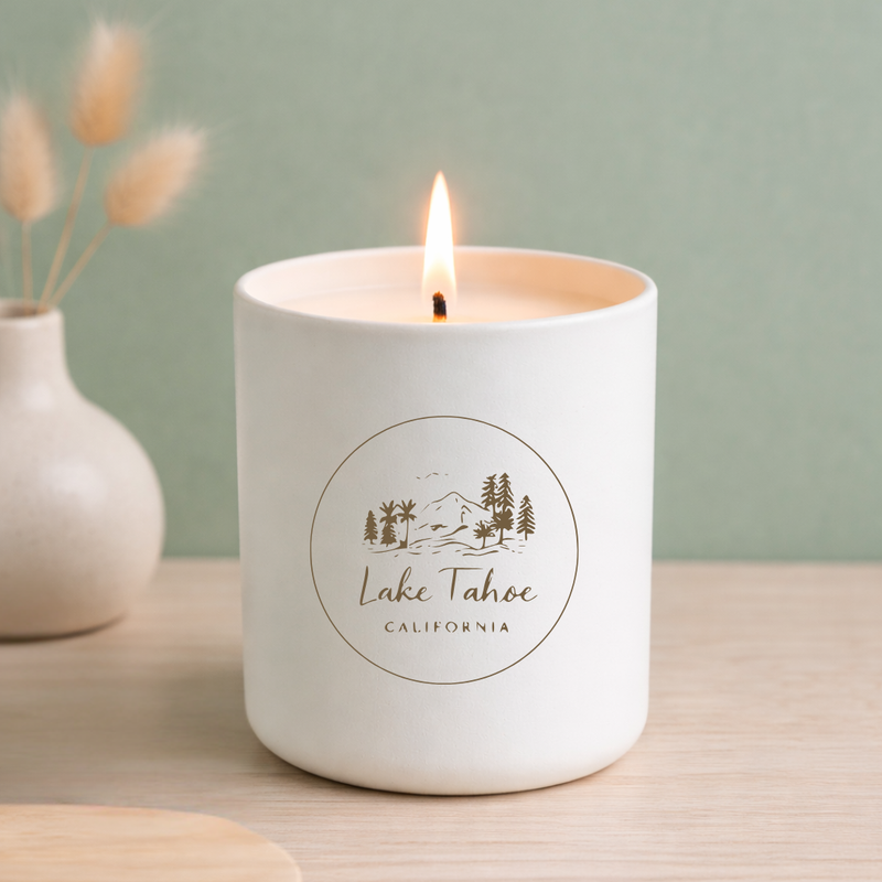 Candle in a white container with 'Lake Tahoe, California' branding on a light wooden surface.
